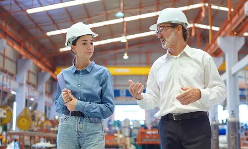 Engineering manager and team member reviewing work on a manufacturing floor