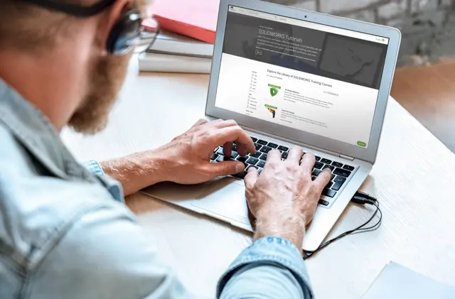 Engineer working through a self-paced SOLIDWORKS lesson on a laptop